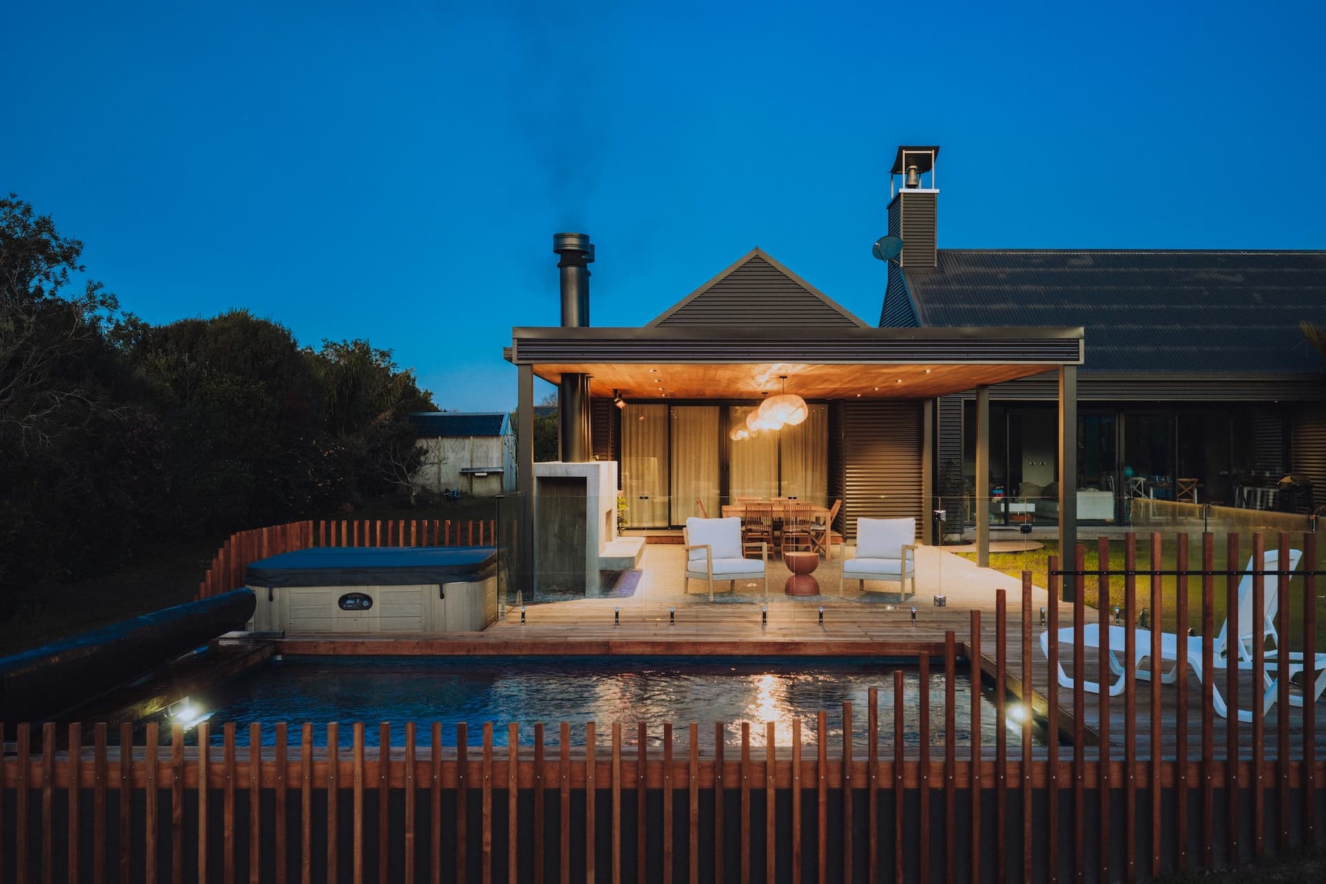 Mangawhai Heads outdoor living - pool and covered pavilion at dusk